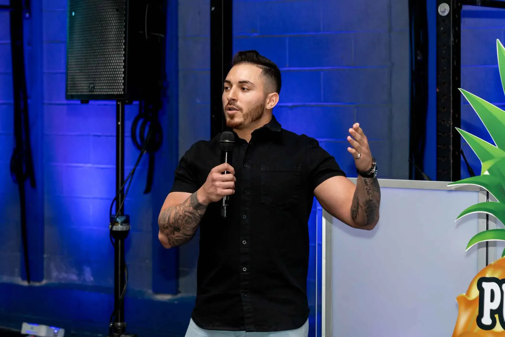 A man in a black shirt is standing in front of a microphone.