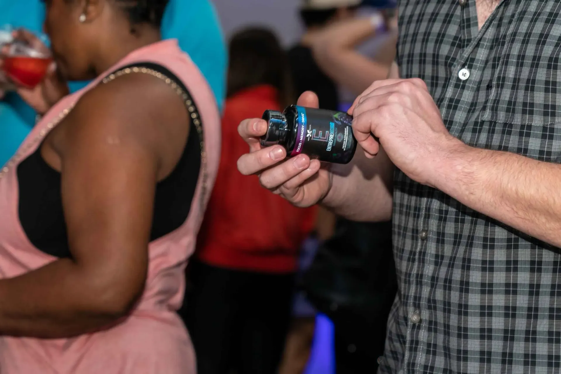 A man in a plaid shirt is holding a bottle in his hand.