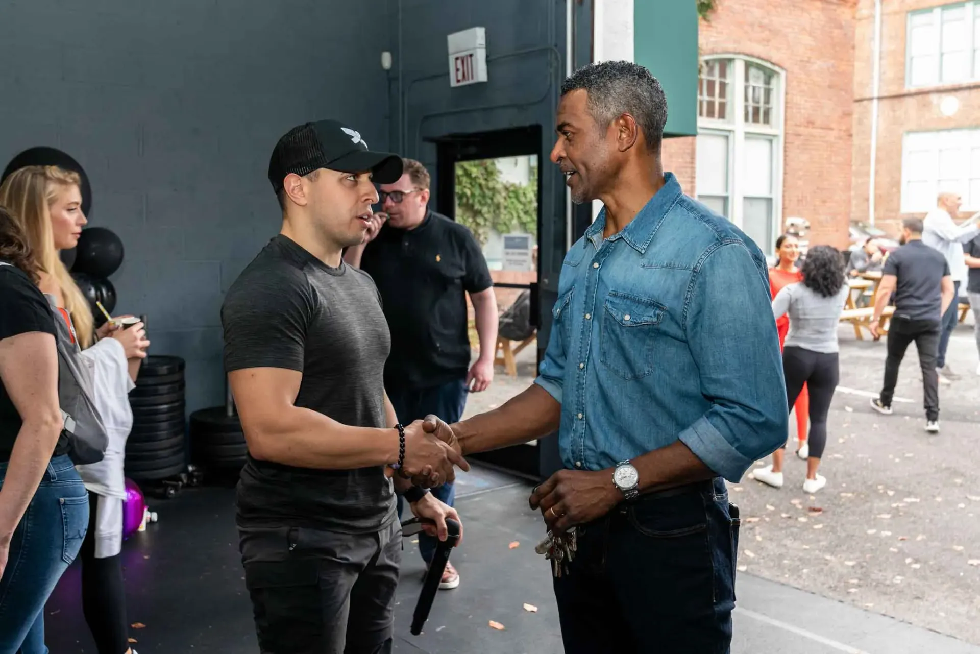 Two men are shaking hands in front of a crowd of people.