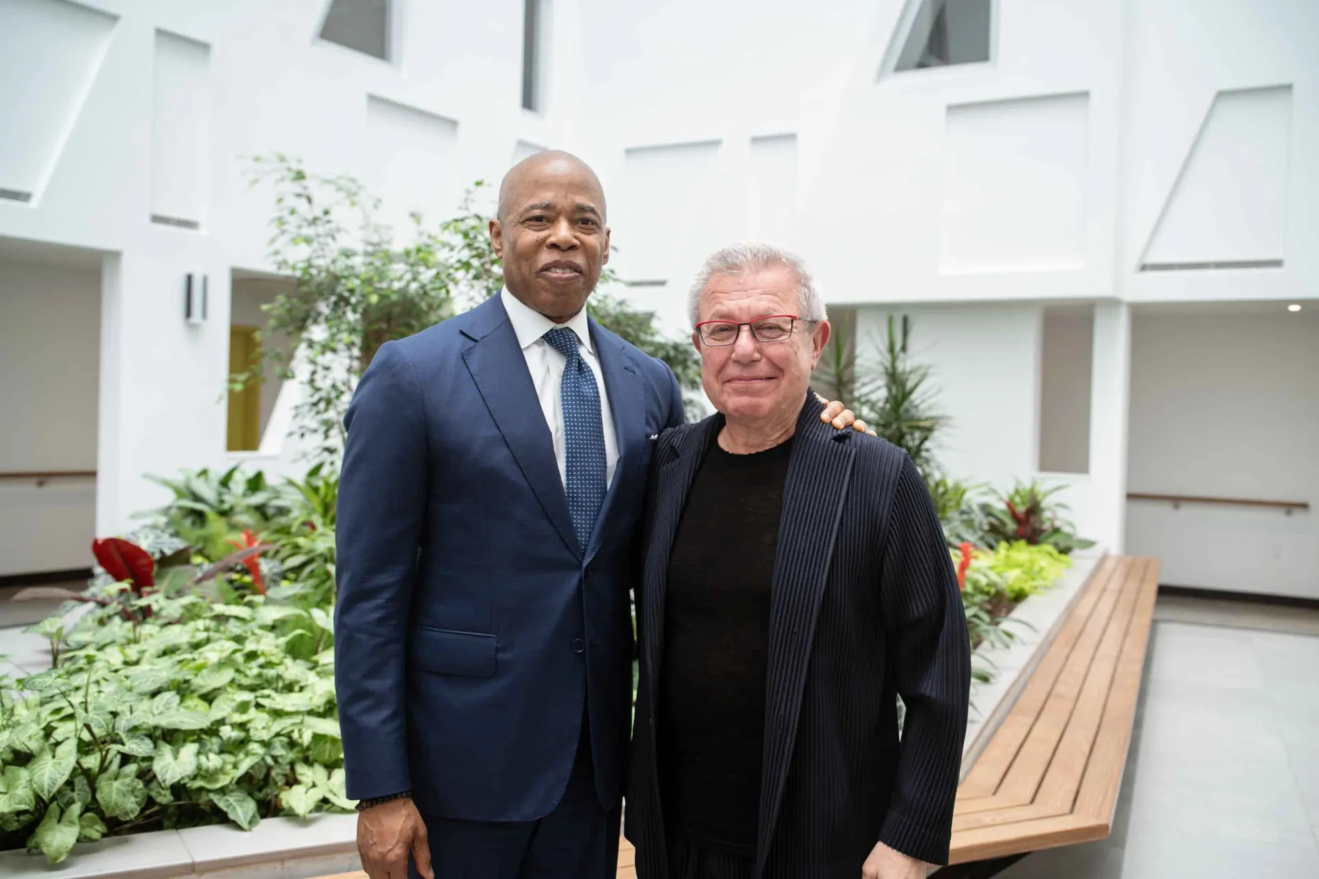 Two men in suits and ties are standing next to each other in a courtyard.