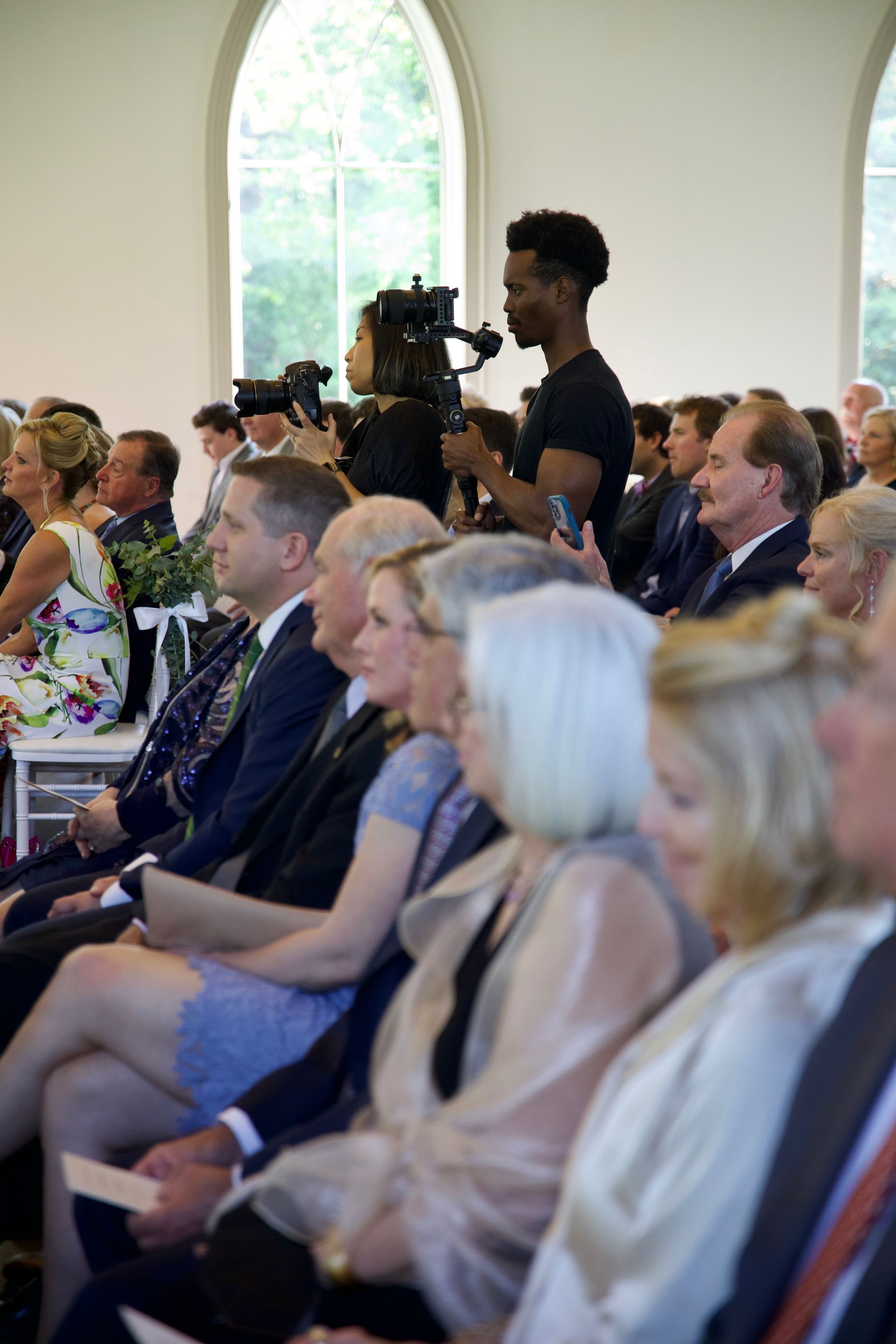 A group of people are sitting in a church watching a wedding ceremony.
