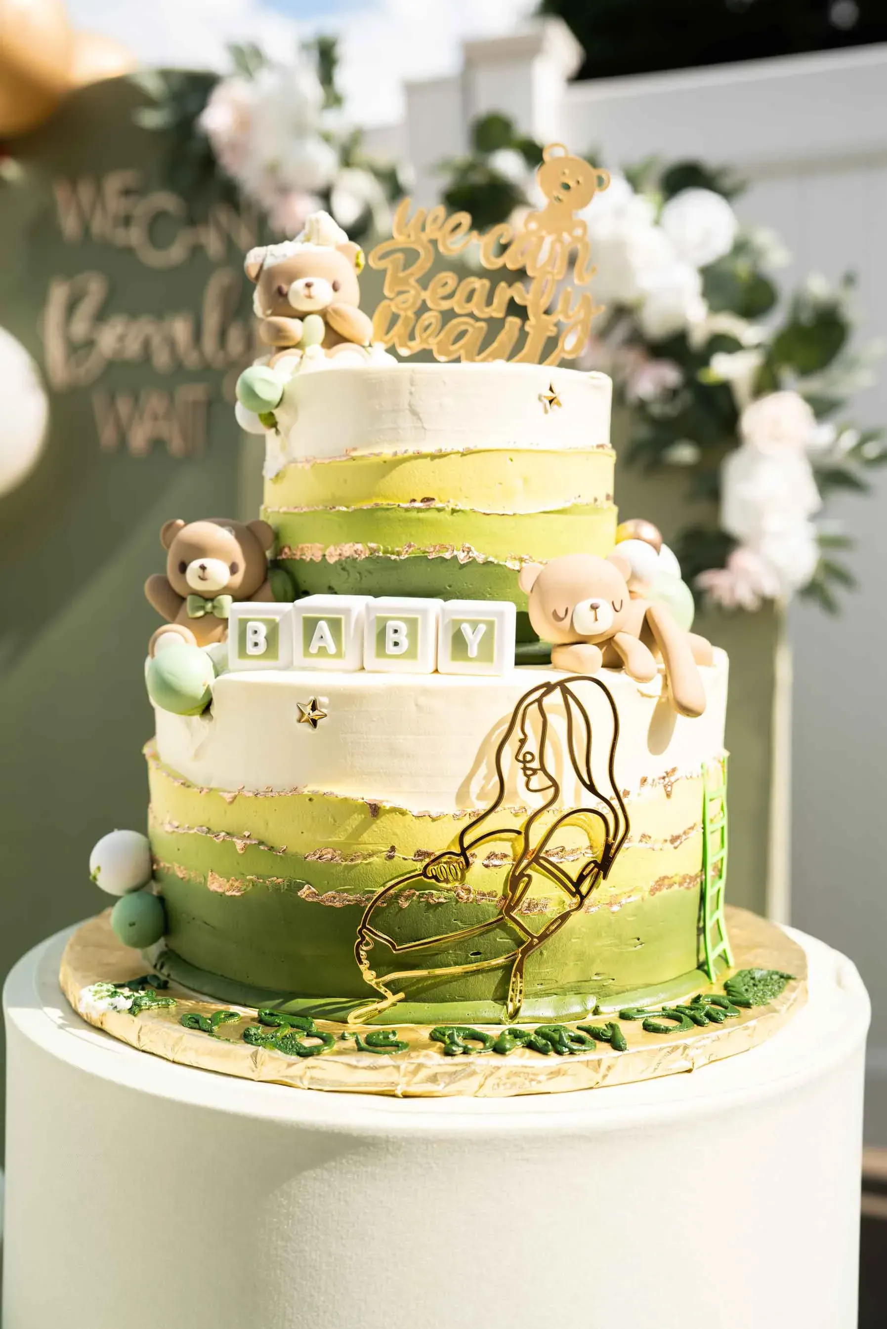 A baby shower cake with teddy bears on it is sitting on top of a table.