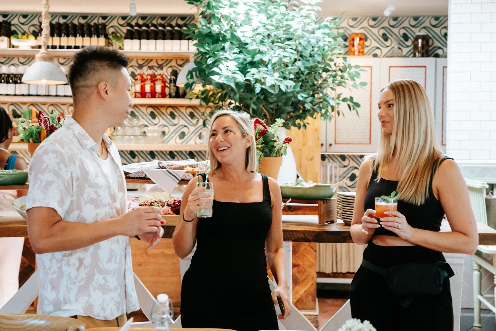 A man and two women are standing next to each other in a restaurant.