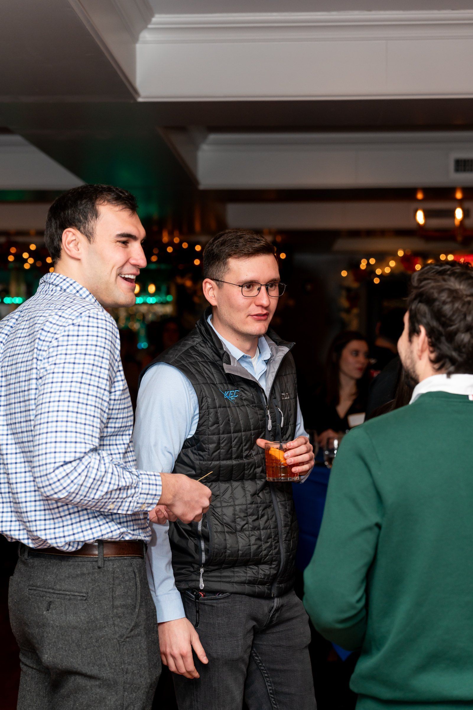 Colleagues laughing over cocktails at a company holiday celebration