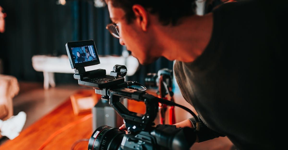 A man is looking at the screen of a video camera.