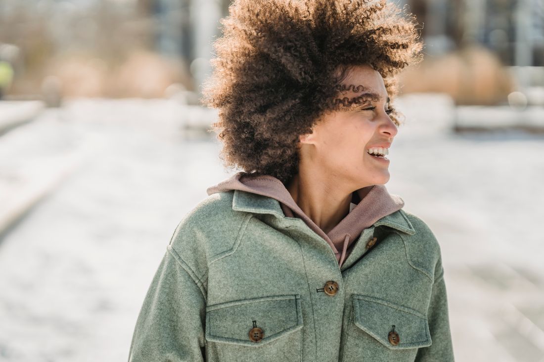 Person in a green jacket smiling outdoors on a snowy day