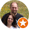 Two adults posing outdoors, one with an orange star badge in the corner.