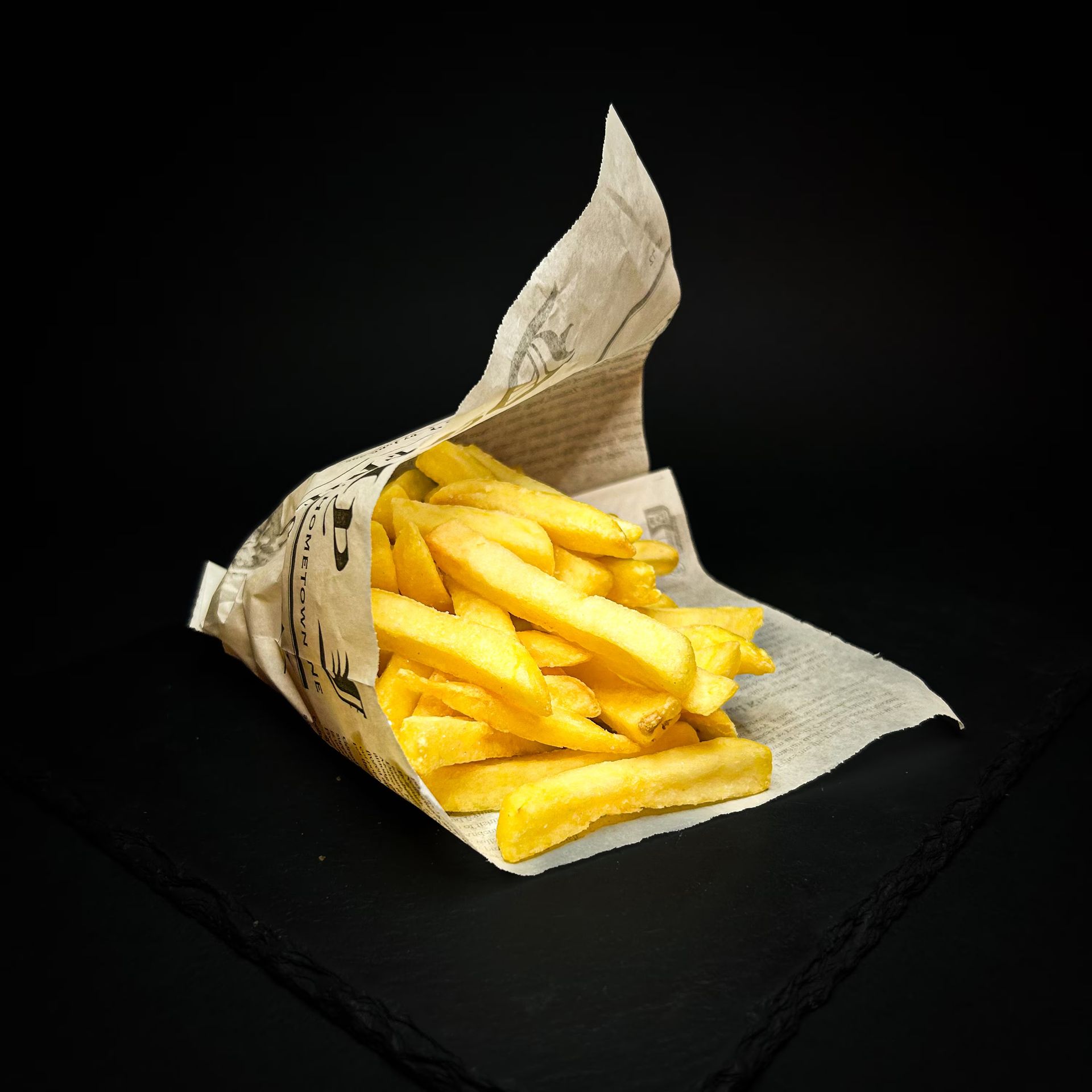 Patatine fritte in un cono di carta su uno sfondo nero