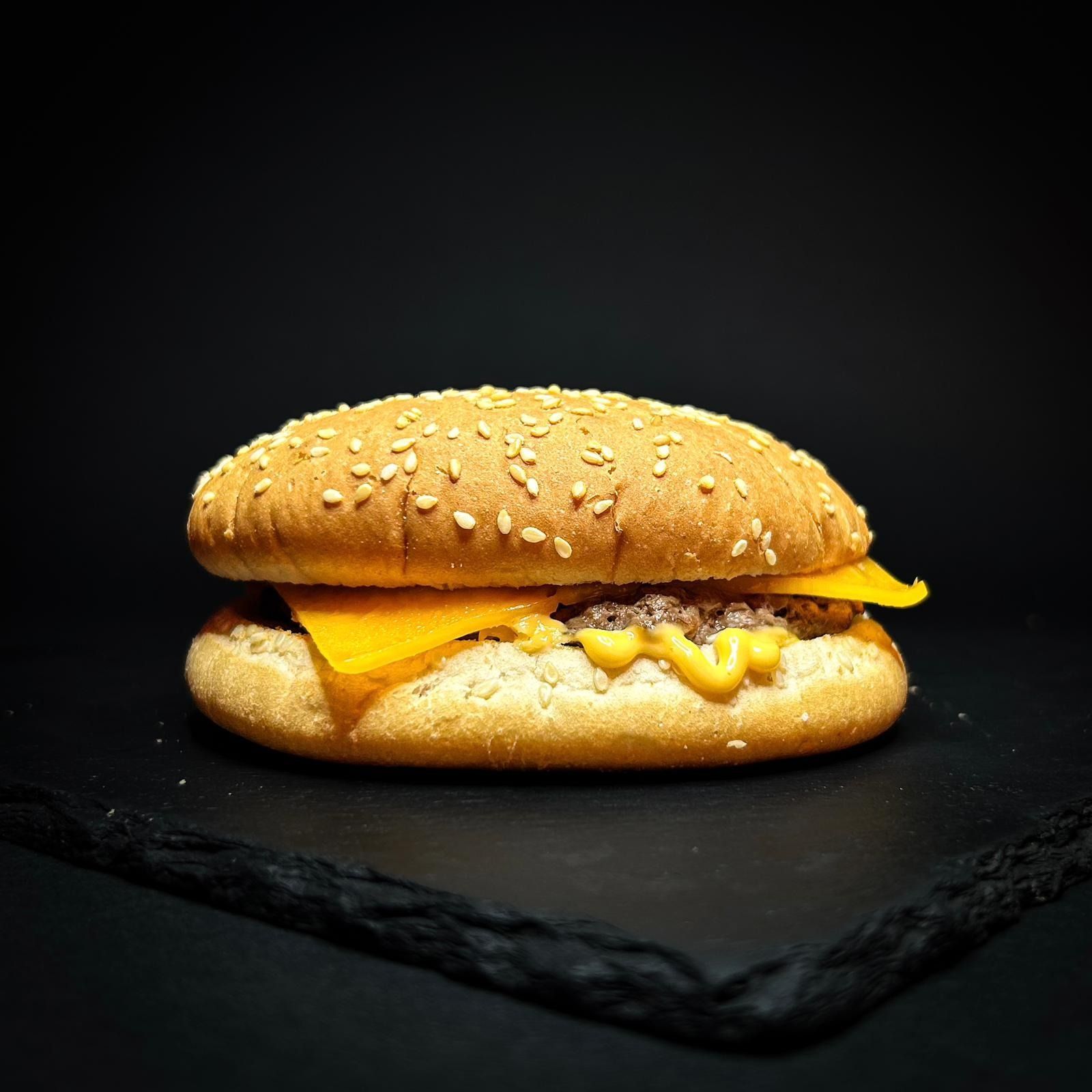 Cheeseburger ai semi di sesamo con cheddar fuso su una superficie di ardesia scura