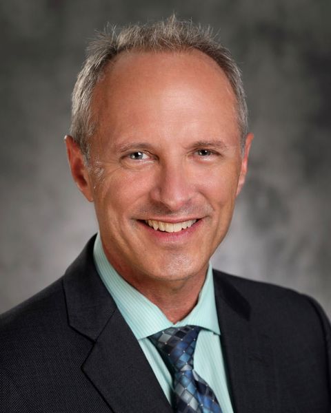 A man in a suit and tie is smiling for the camera