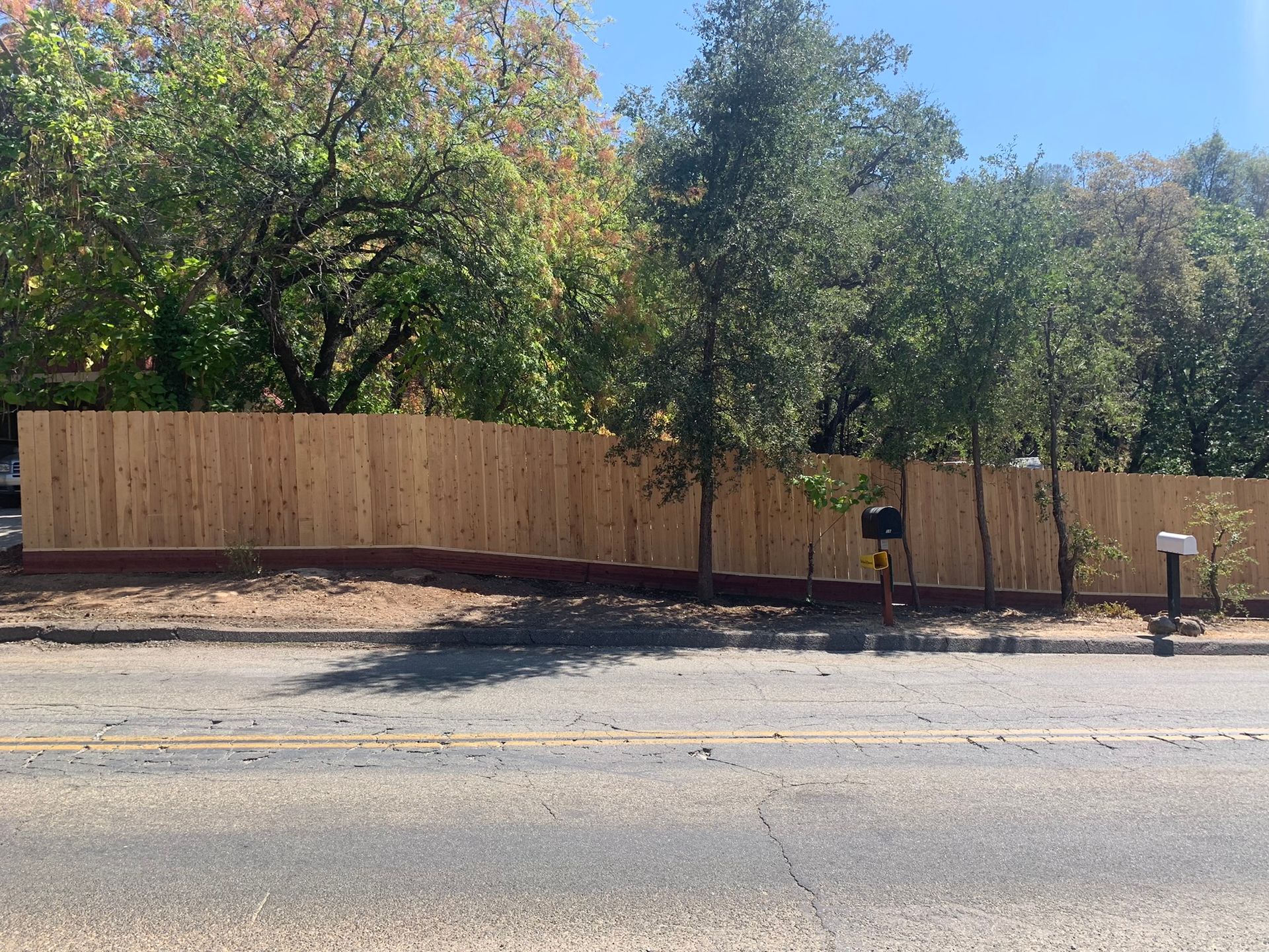 A wooden fence is sitting on the side of the road next to a mailbox.