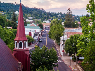 An aerial view of a small town with a red steeple in the middle of the street.