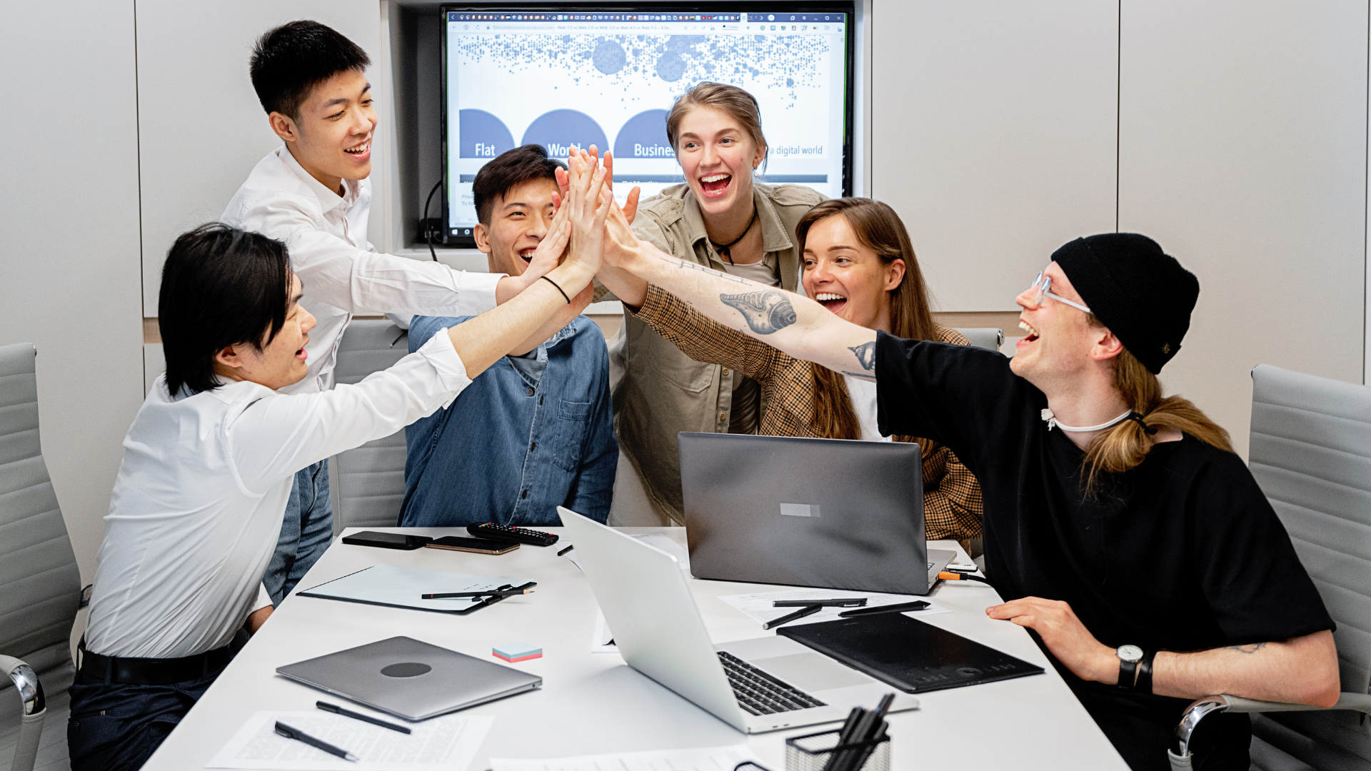 A group of people are giving each other a high five in a conference room.
