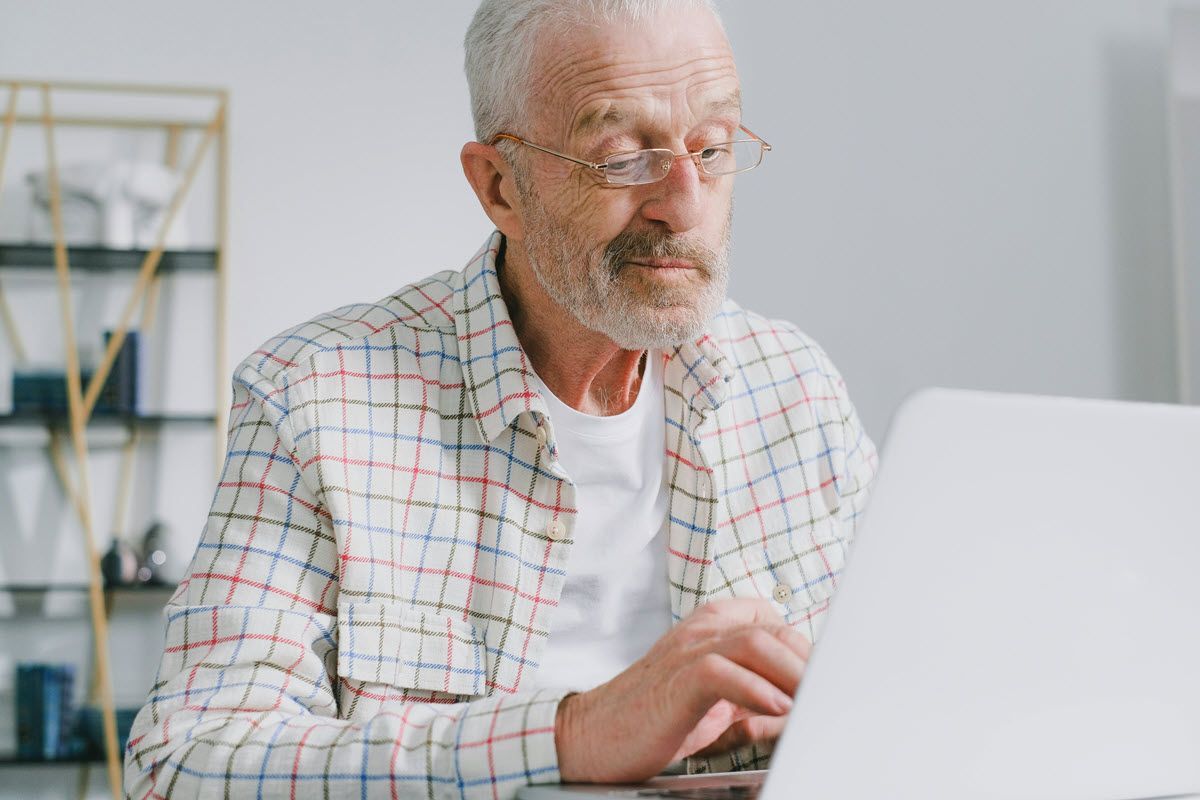 gray hair old man and a neatly trimmed gray beard wearing thin, gold glasses that rest on his nose