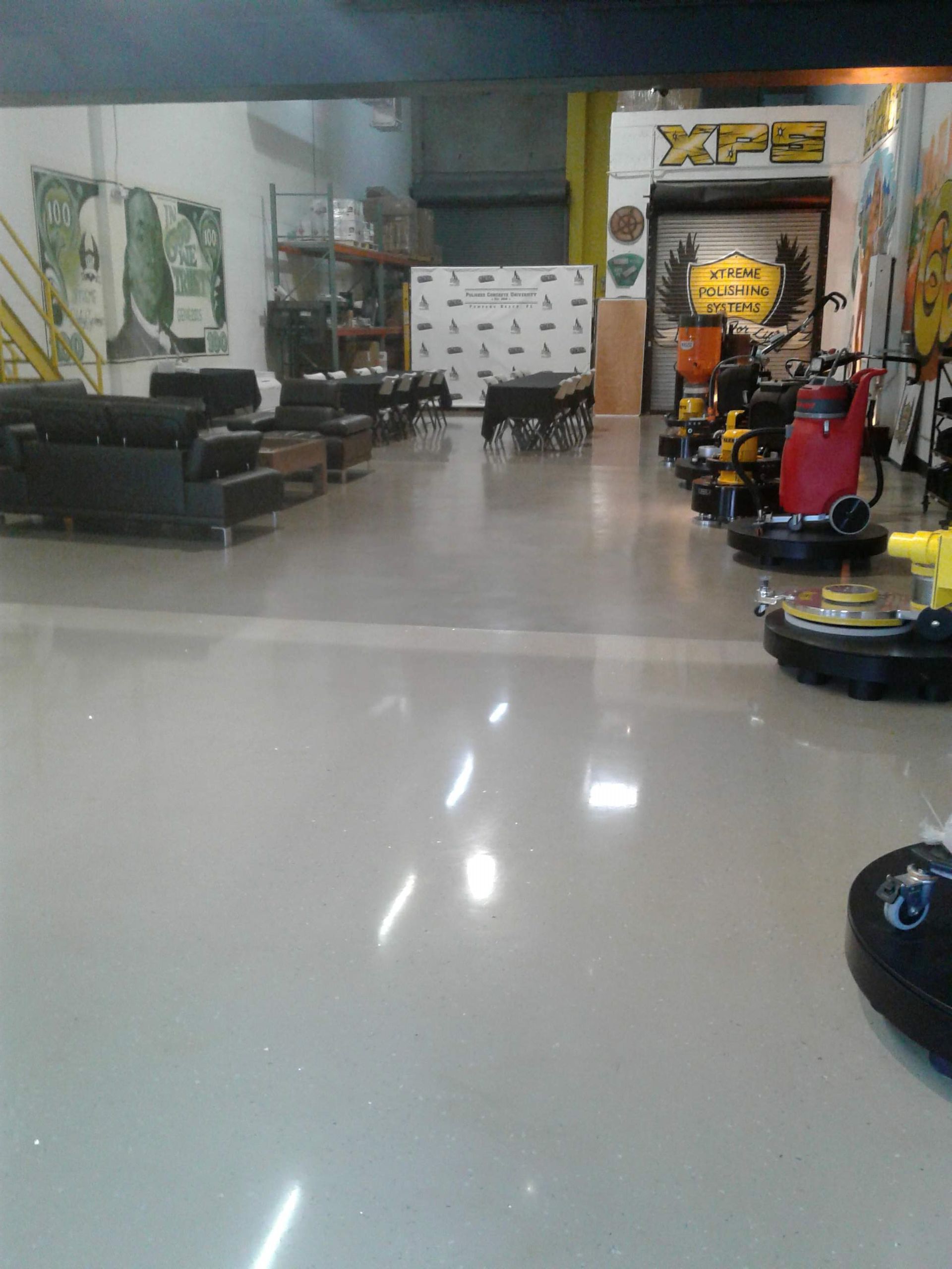 Interior of a warehouse with shiny floors. Go-karts, furniture, and a sign that says 