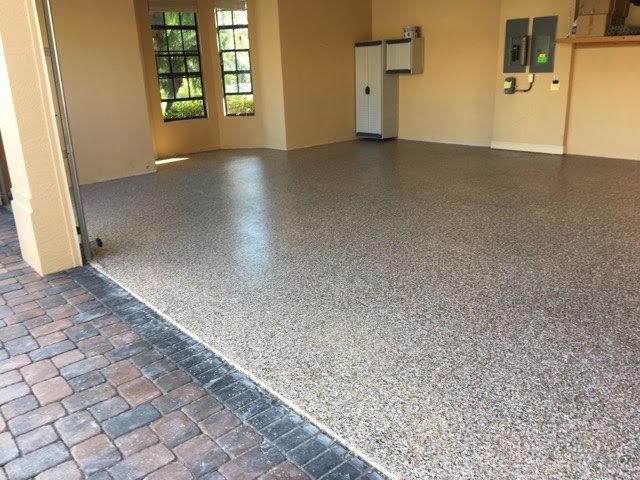 Garage with a speckled epoxy floor. Open doorway reveals brickwork.