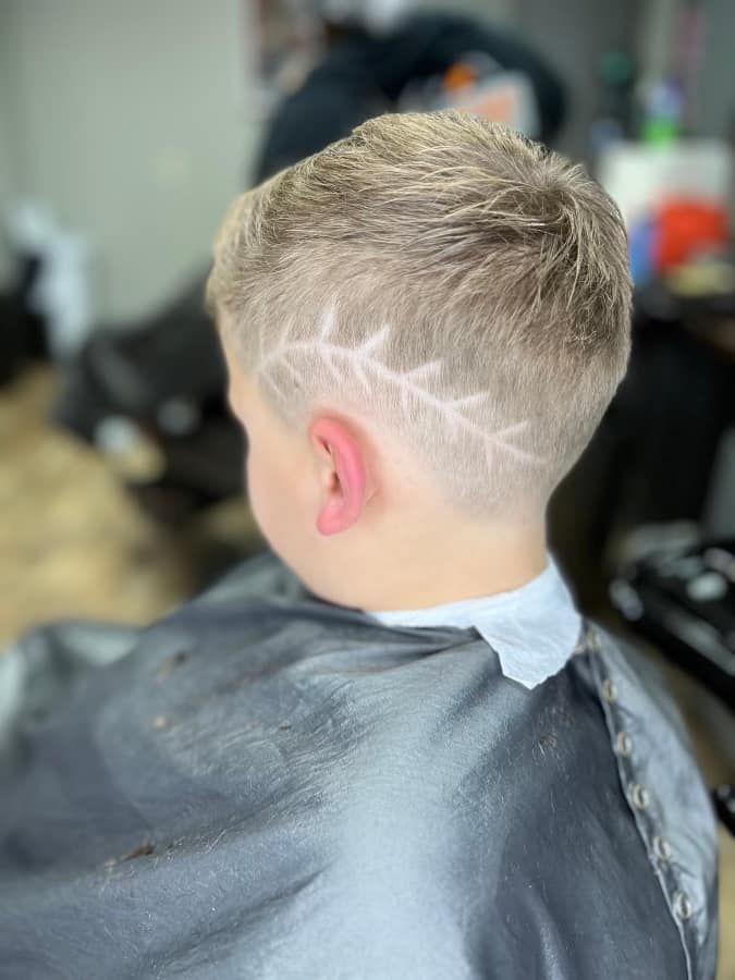 Boy with a short blond haircut and shaved zigzag design at a barber shop