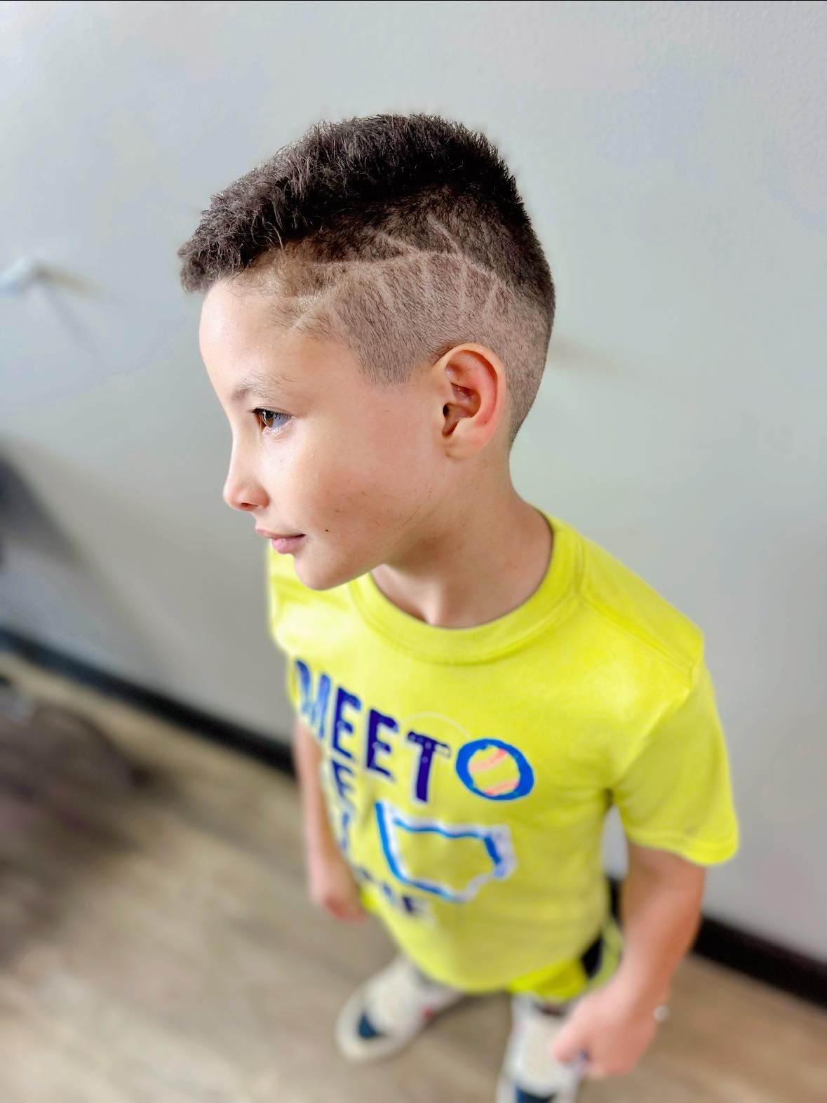 Young child in a neon yellow T-shirt looking to the side indoors