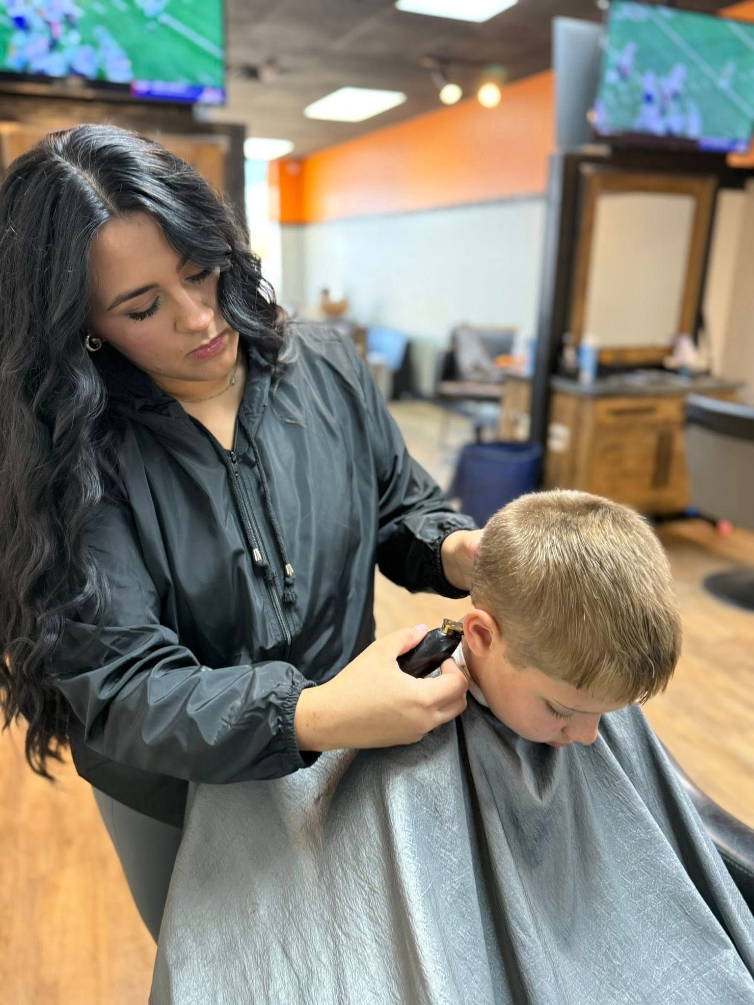 Hair stylist using clippers to cut a child's hair in a salon.