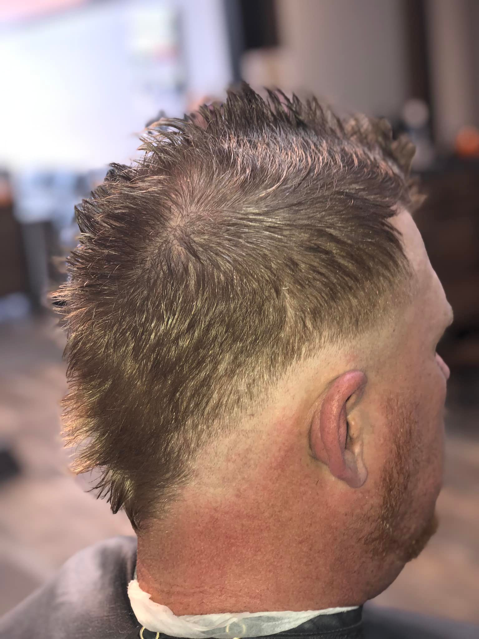 Close-up of a man's spiky haircut with a faded sides haircut, viewed from behind and the side.