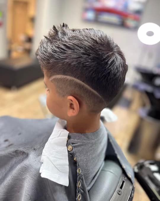 Side-view of a short spiky haircut with faded sides in a barbershop chair