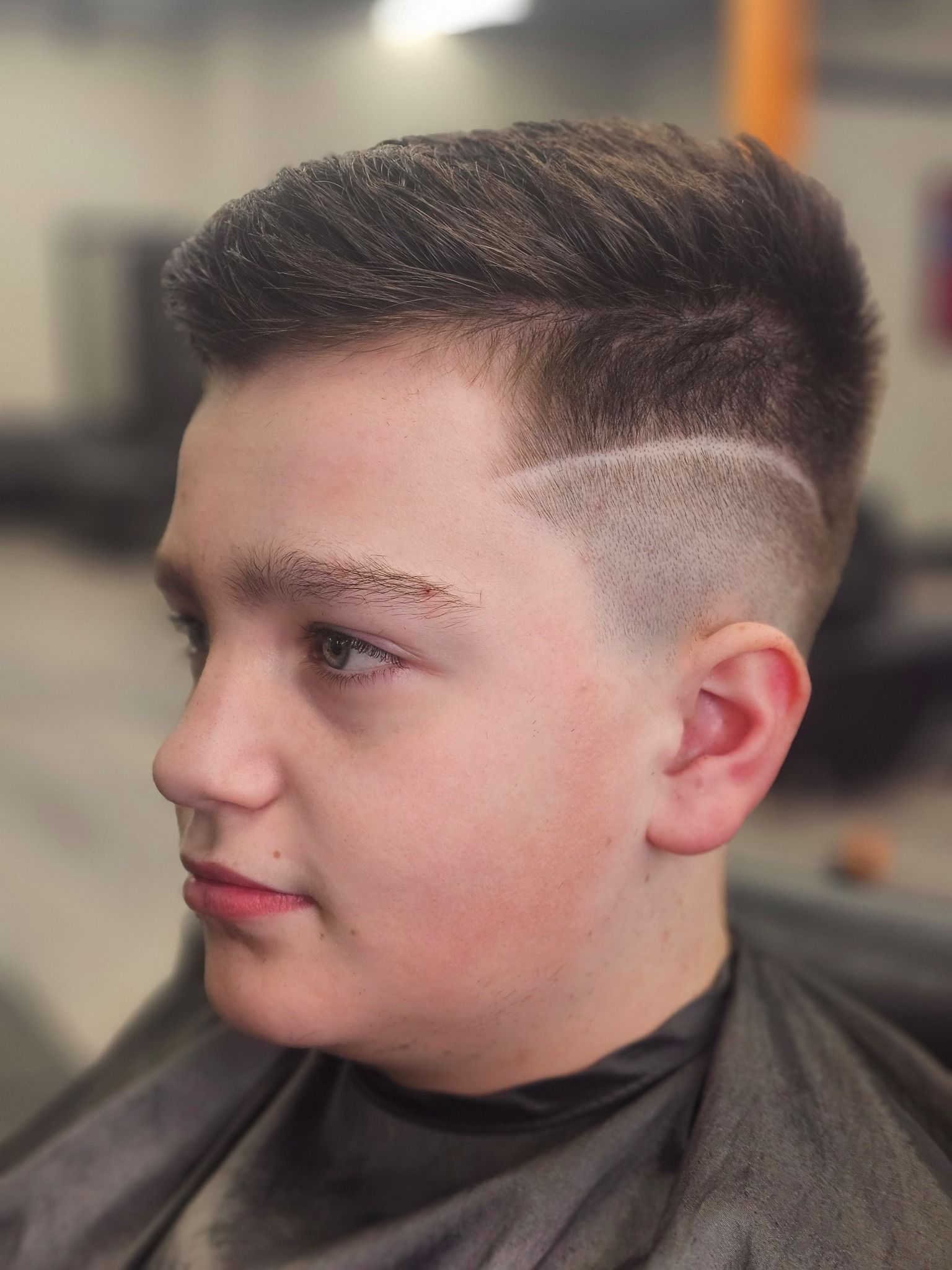Profile view of a man with a modern fade haircut in a barber chair