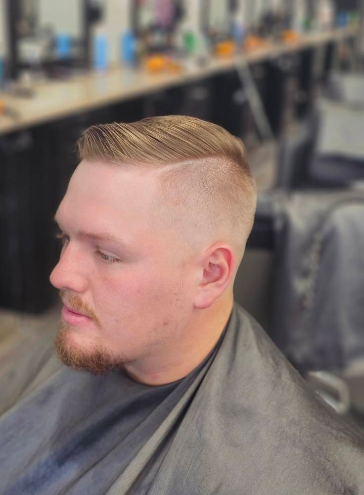 Close-up of a man with a short blond fade haircut and beard getting a haircut in a barbershop