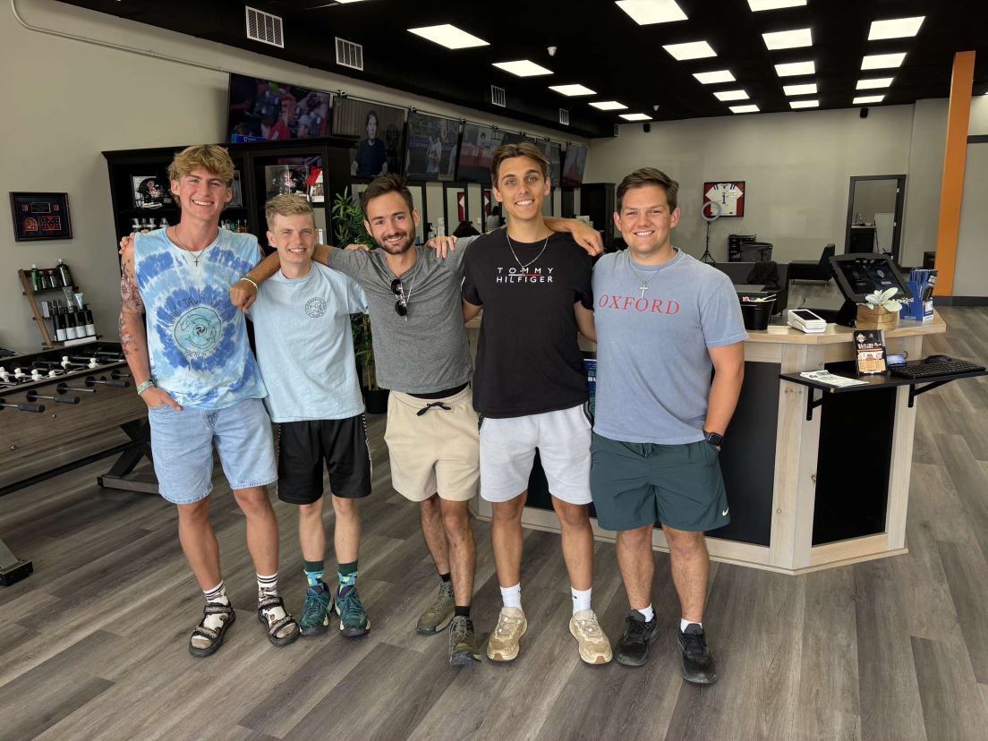 Five people standing together in a store, smiling, posing for a photo.