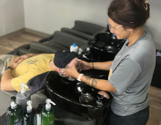 A person washing a customer's hair at a salon.