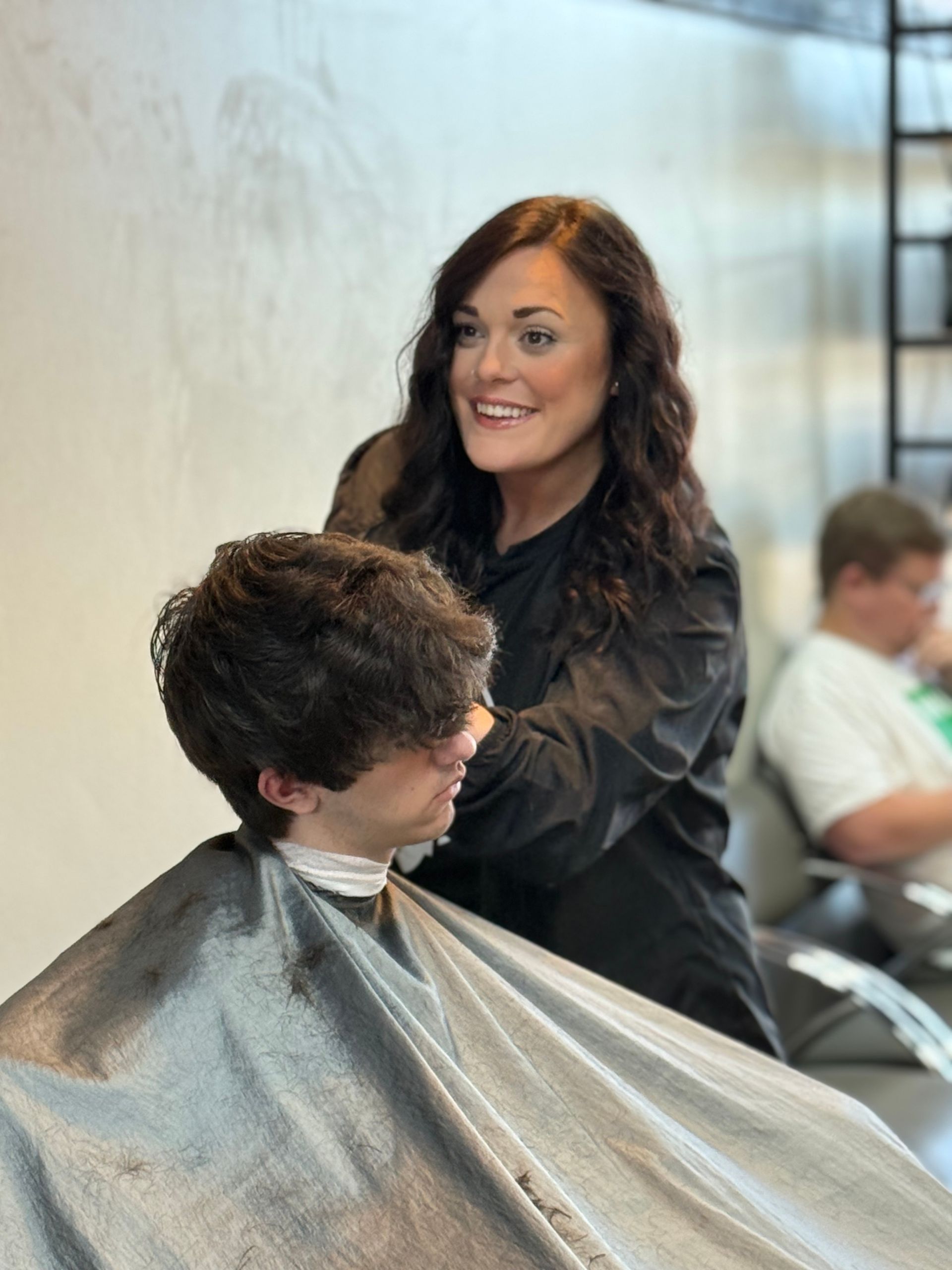 Woman cutting man's hair in a salon. Man makes a surprised face.