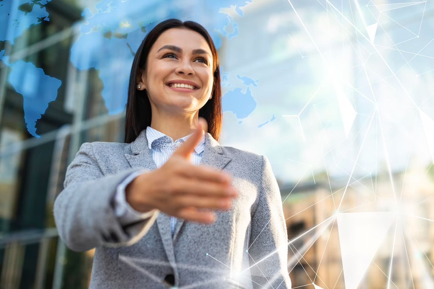 A person in a gray blazer extends a hand for a handshake, with a translucent world map and digital network overlay.