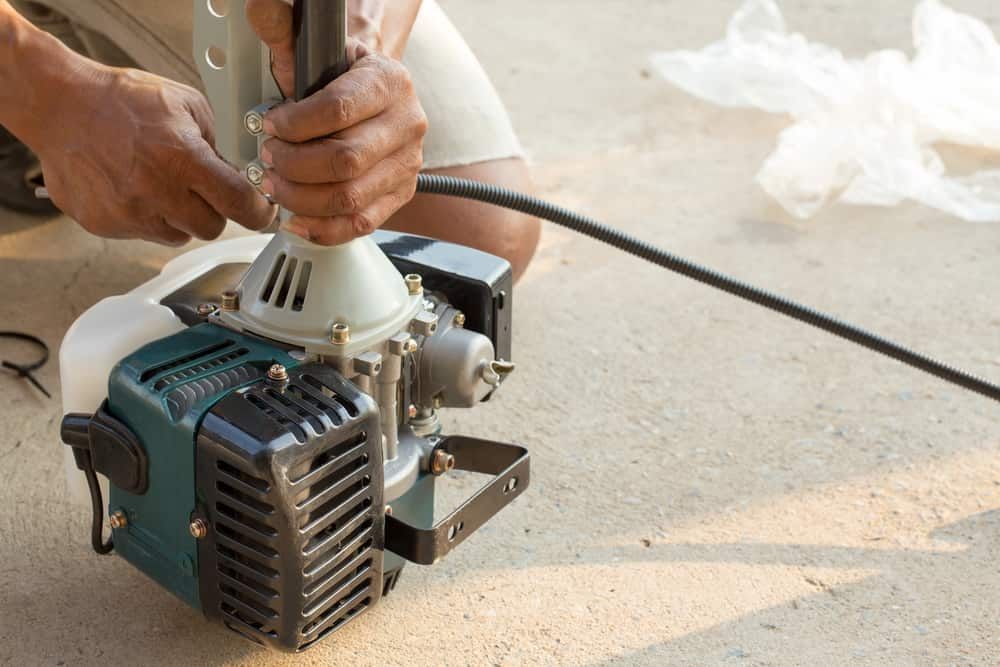 A Man Is Fixing A Lawn Mower On The Ground  — Shamrock Mower & Motorcycle Repairs in Braemar, NSW