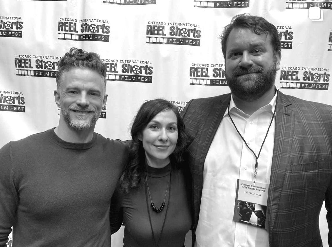 Three people posing for a photo. A woman in the middle with two men on either side, smiling, at a film festival.