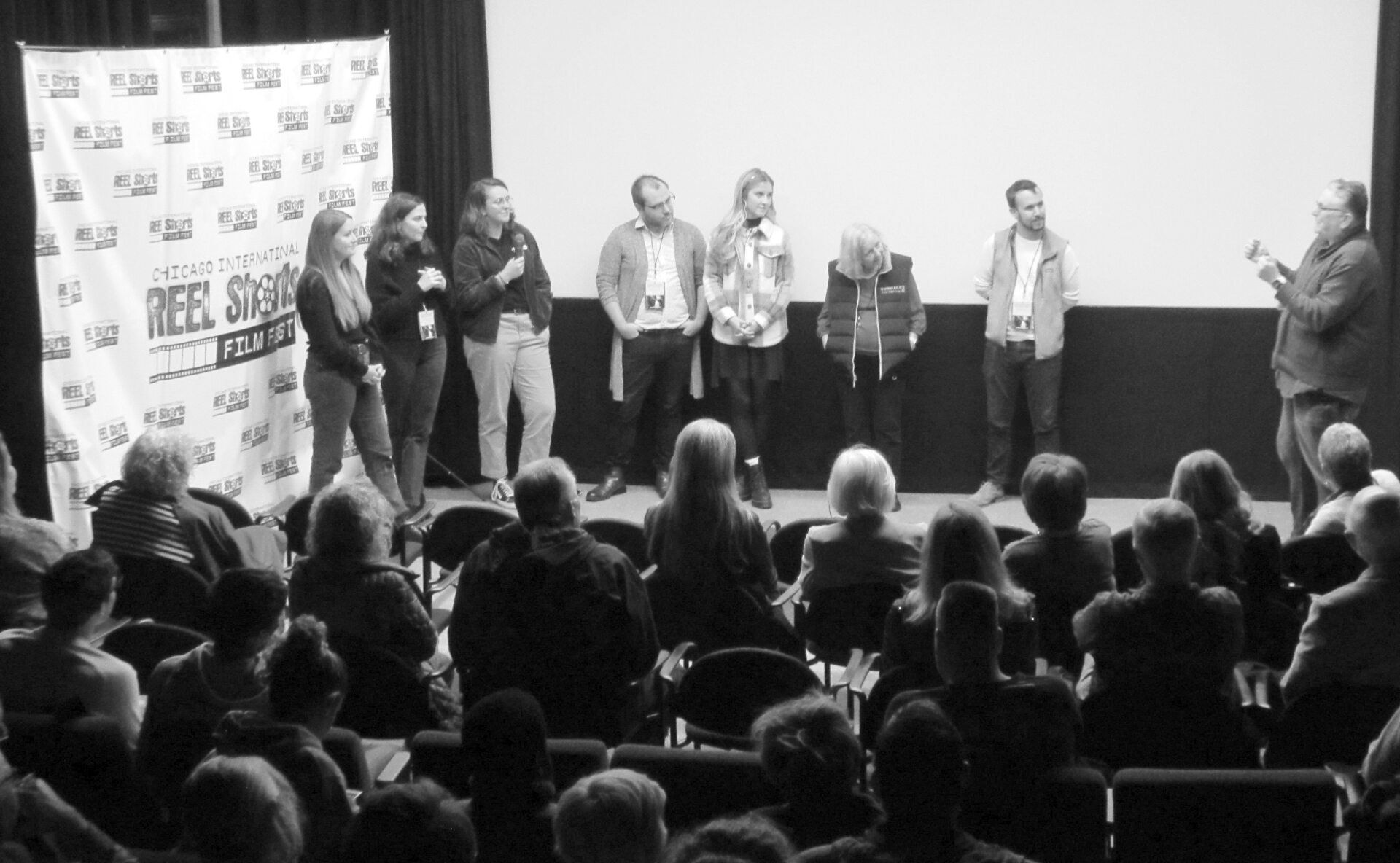 A panel on stage at a film festival, facing an audience.