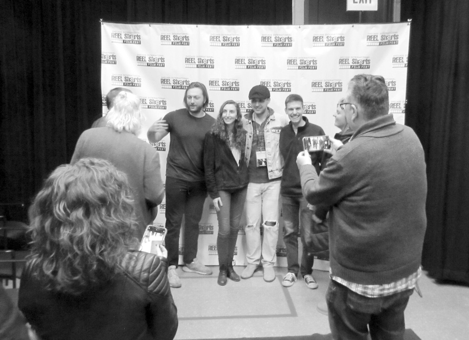 People pose for a photo in front of a backdrop. A photographer takes the picture.