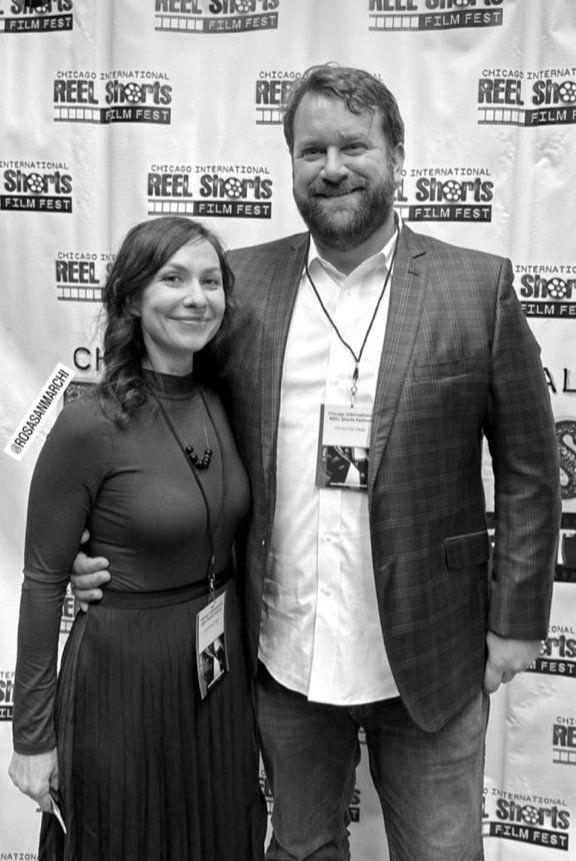 A man and a woman pose together at a film festival. Black and white photo.