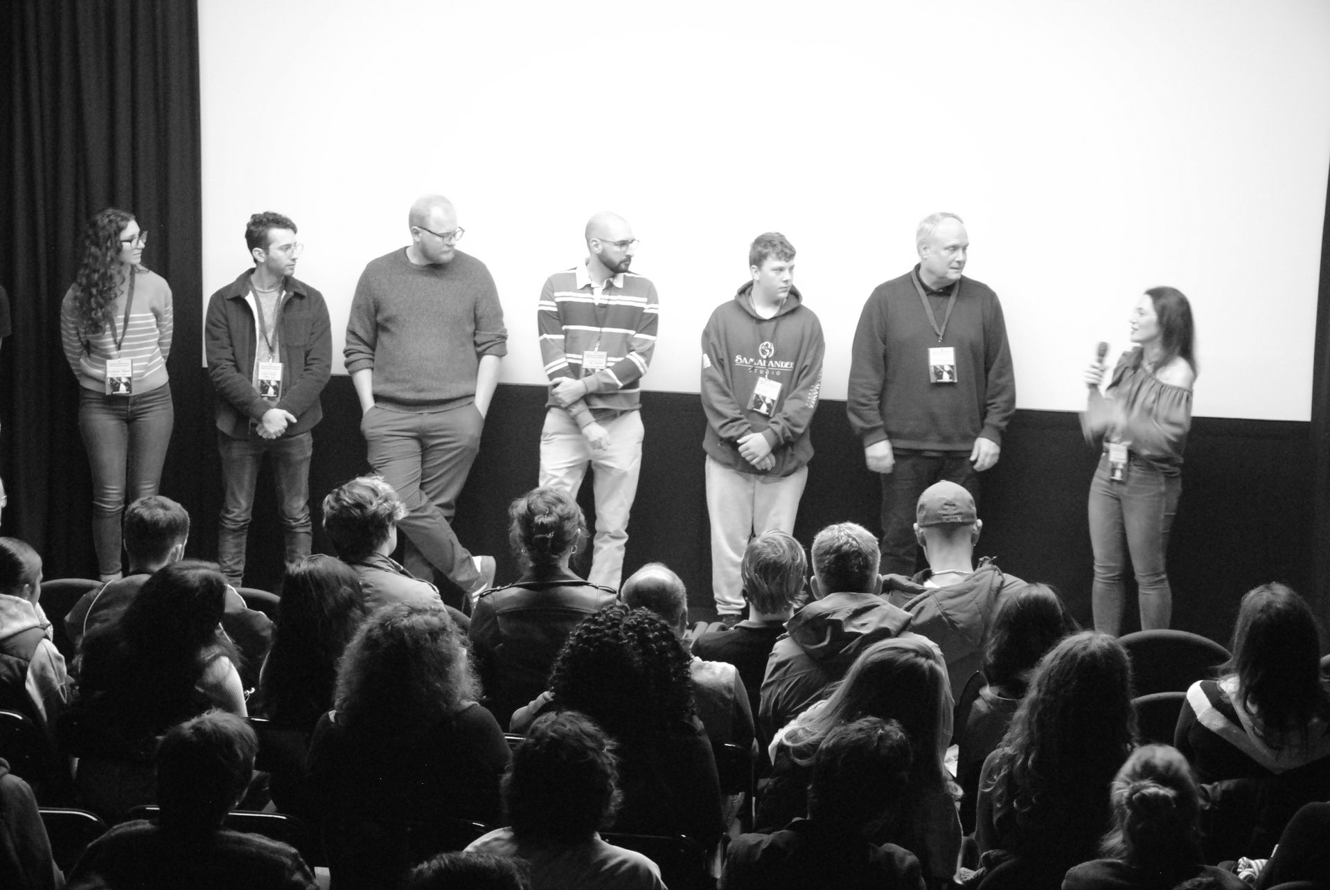 Panel of people on stage in front of an audience. Black and white photo.