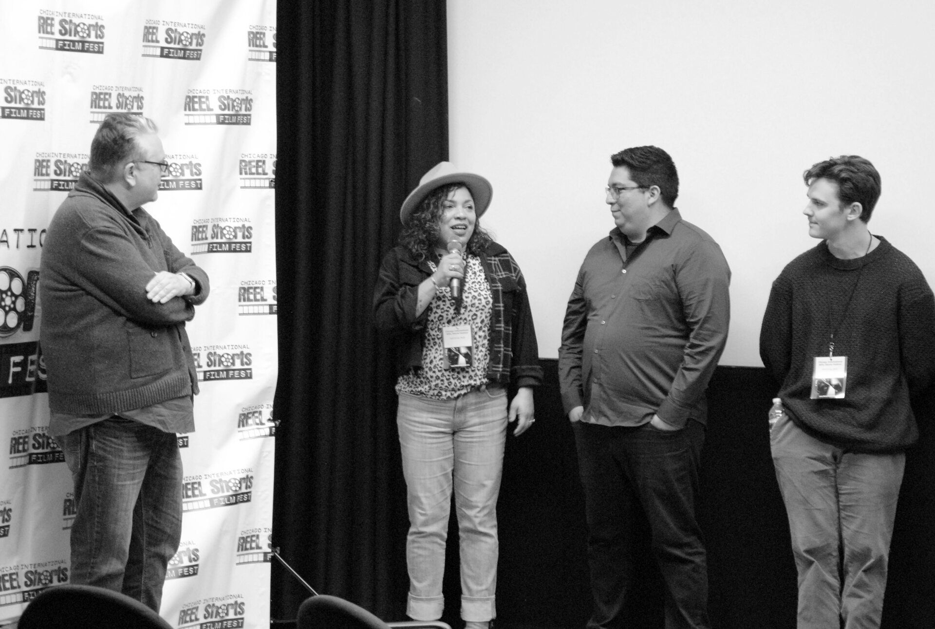 Panel of four people on stage, two holding microphones, at a film festival.