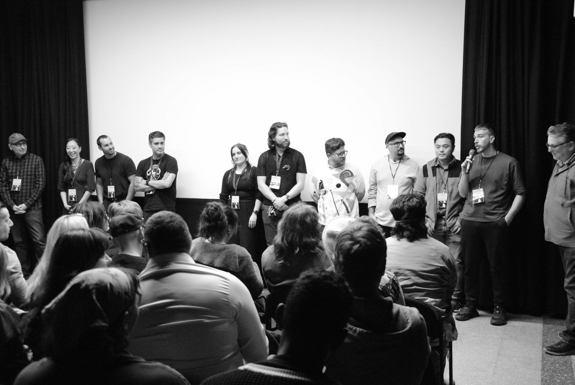 Panel of people on stage in front of an audience. Black and white photo.