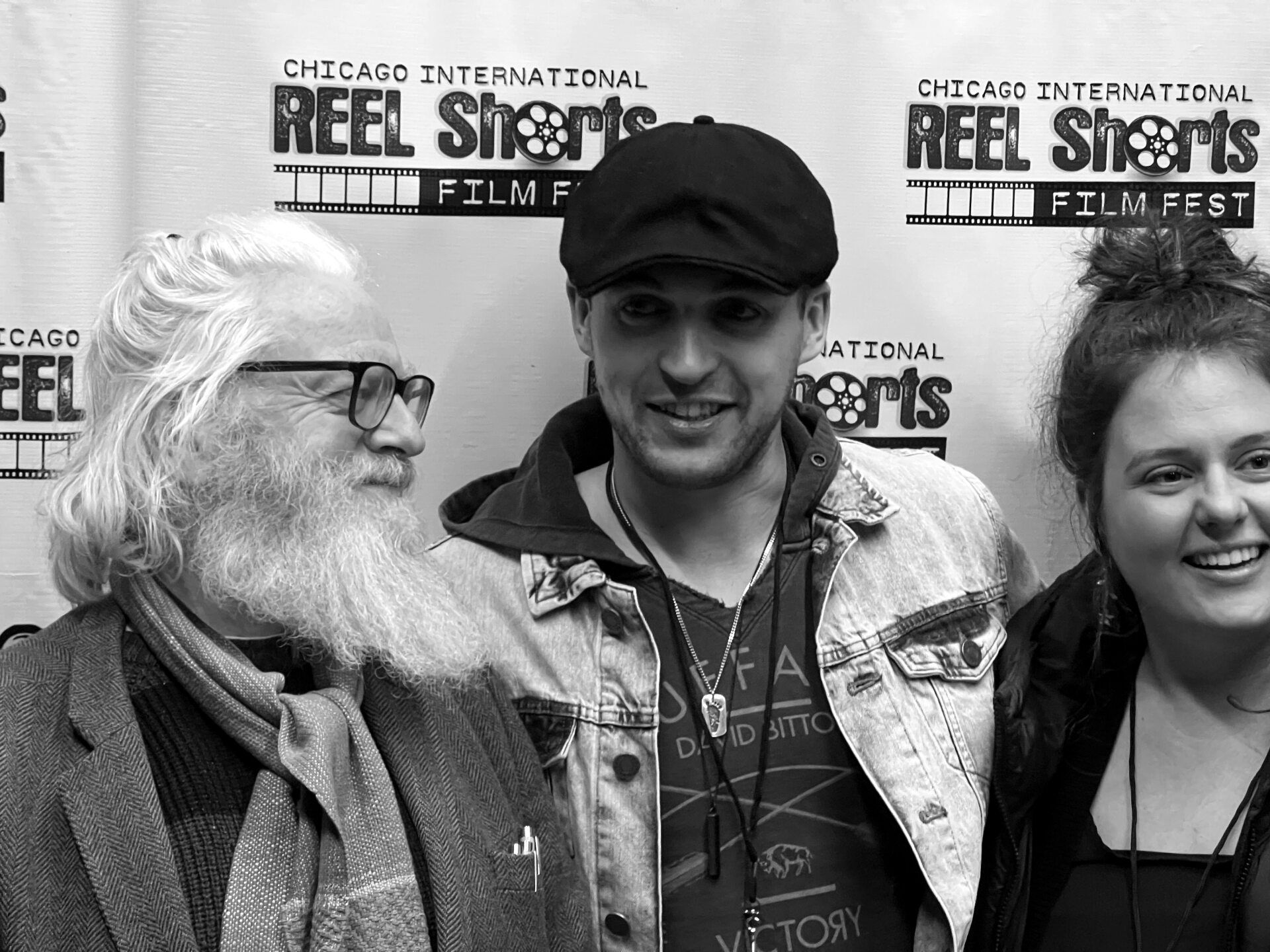 Three people posing at the Chicago International Reel Shorts Film Fest. One man has a long white beard, and one woman smiles.