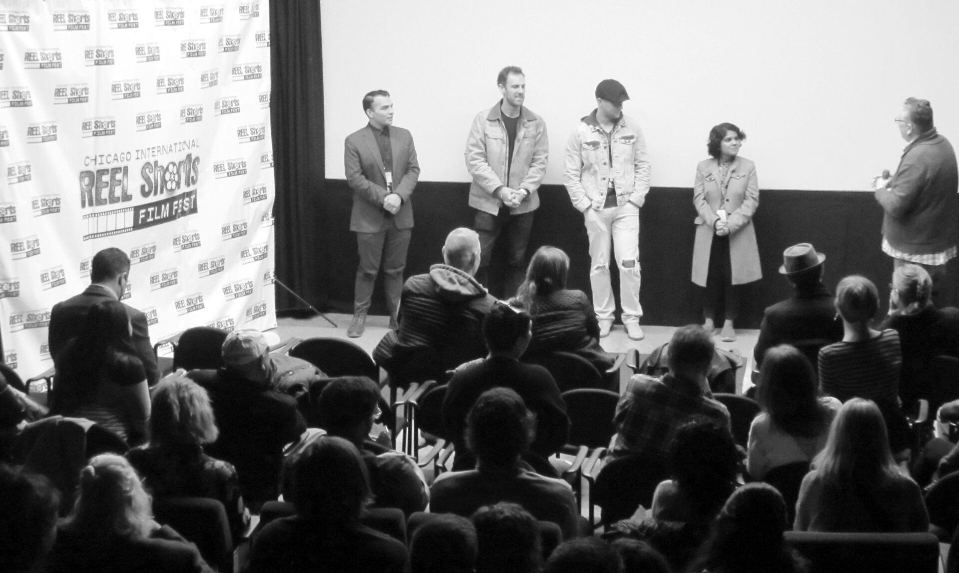 Panel of people on stage in front of an audience at a film festival.