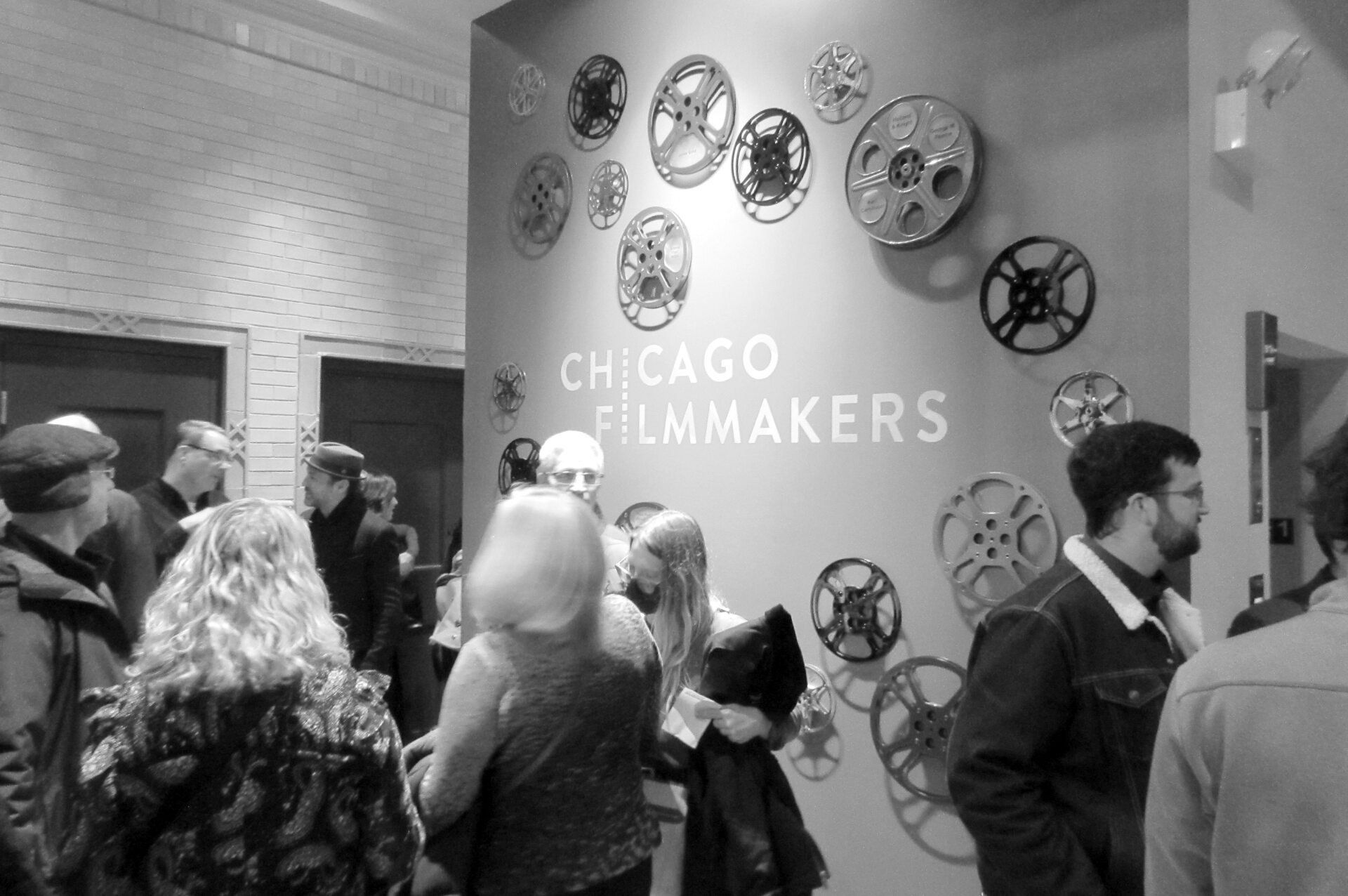 Chicago Filmmakers event: People gathered near wall with film reel decor.