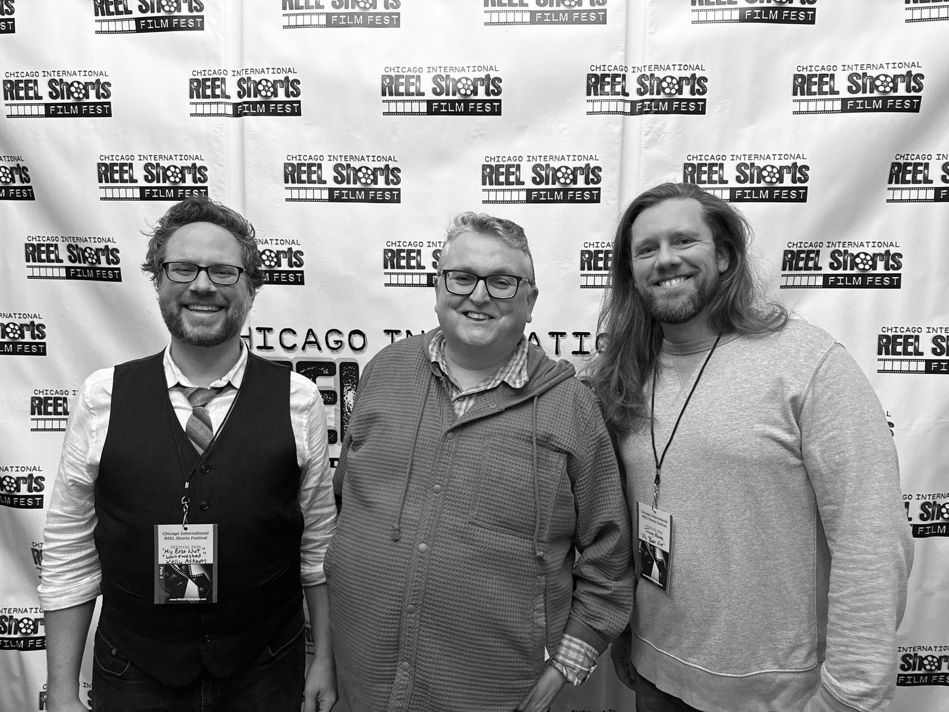 Three men smiling at a film festival, standing in front of a backdrop.