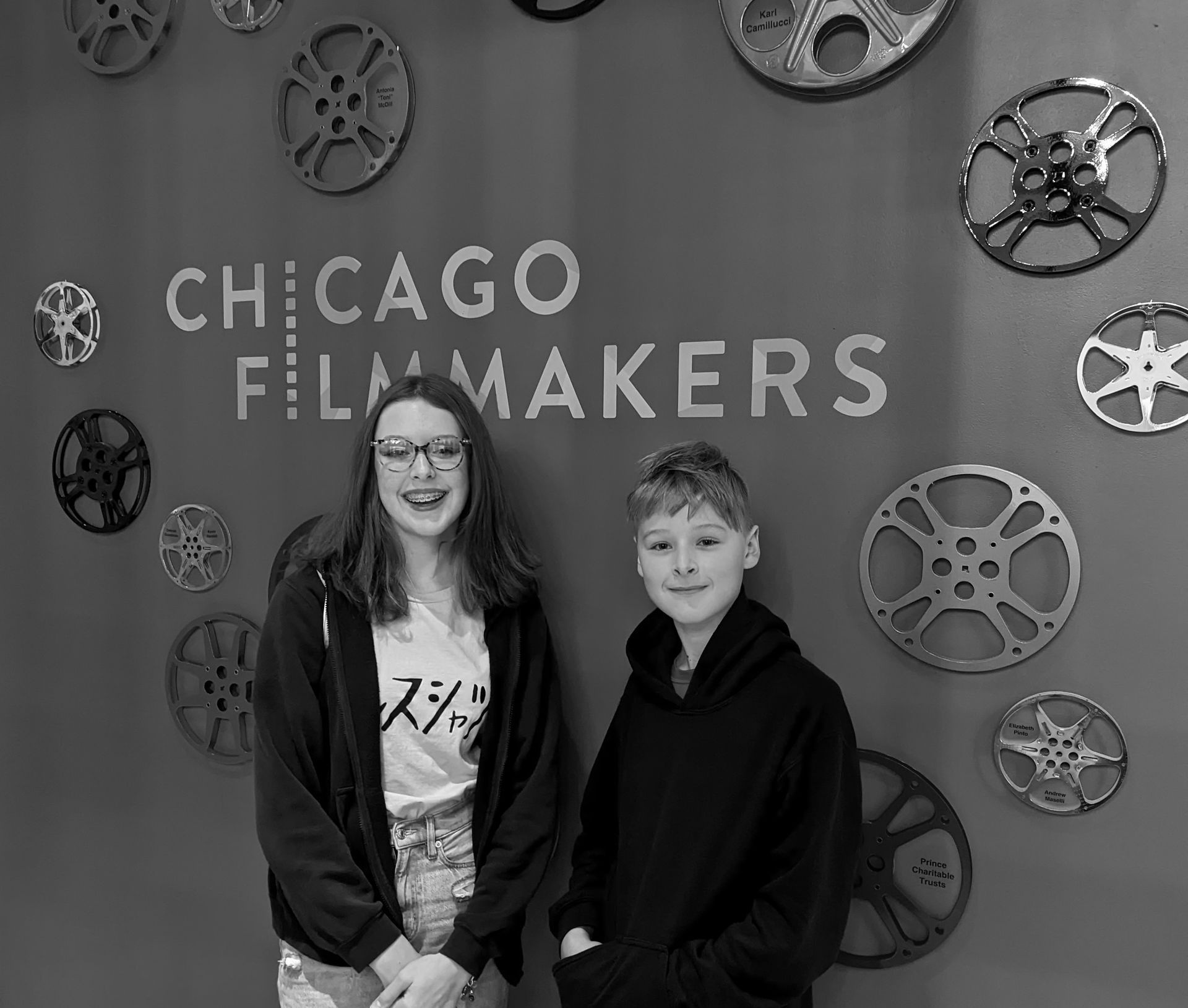 Two people smiling in front of a Chicago Filmmakers sign and film reel decorations.