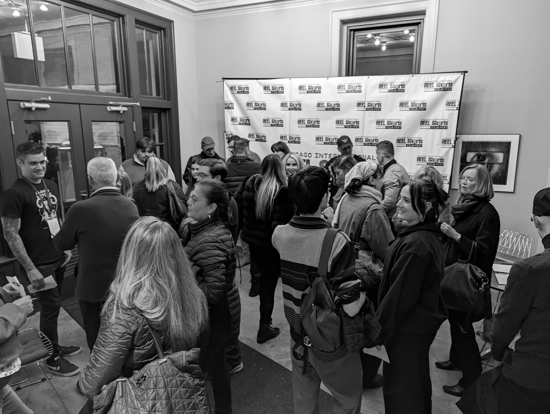 People gathered in a room, likely an event or conference, with a banner as a backdrop.