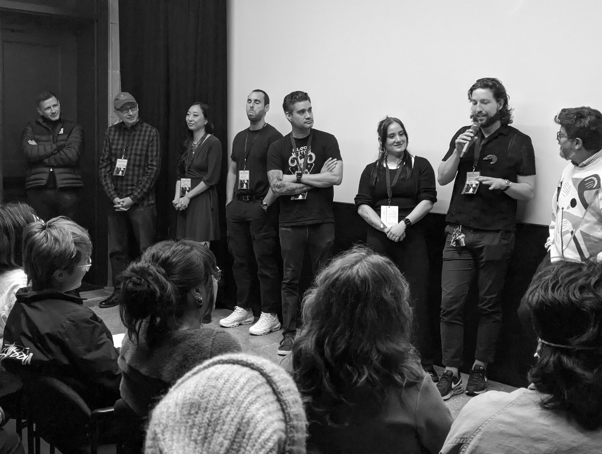 Group of people on a stage, speaking to an audience. Black and white photo.
