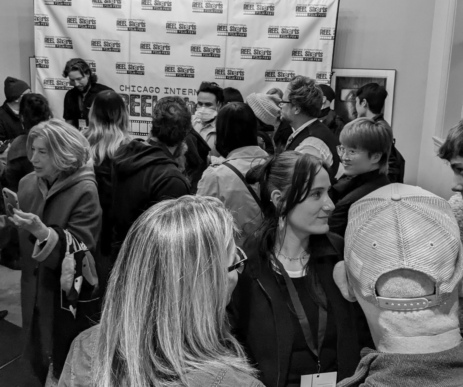 Crowd at a Chicago film festival event. People are mingling in front of a backdrop with the festival logo.