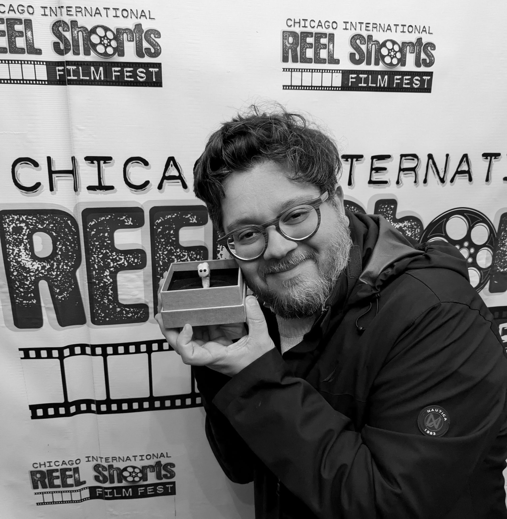 Man holding a film award at the Chicago Reel Shorts Film Fest. Black and white.