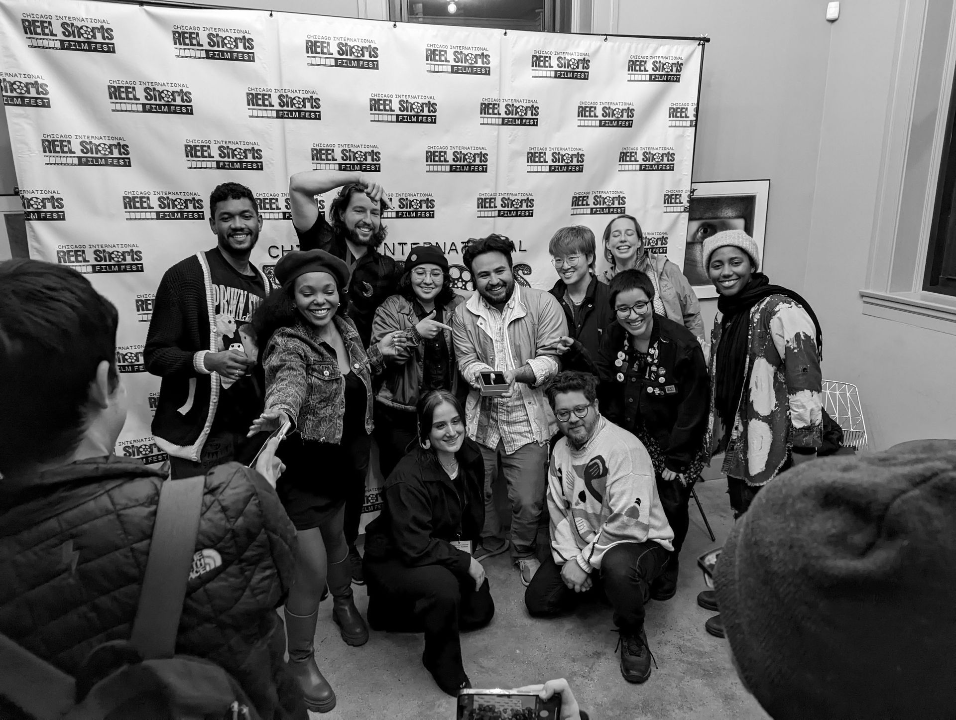 Group of people smiling for a photo in front of a backdrop at an event.