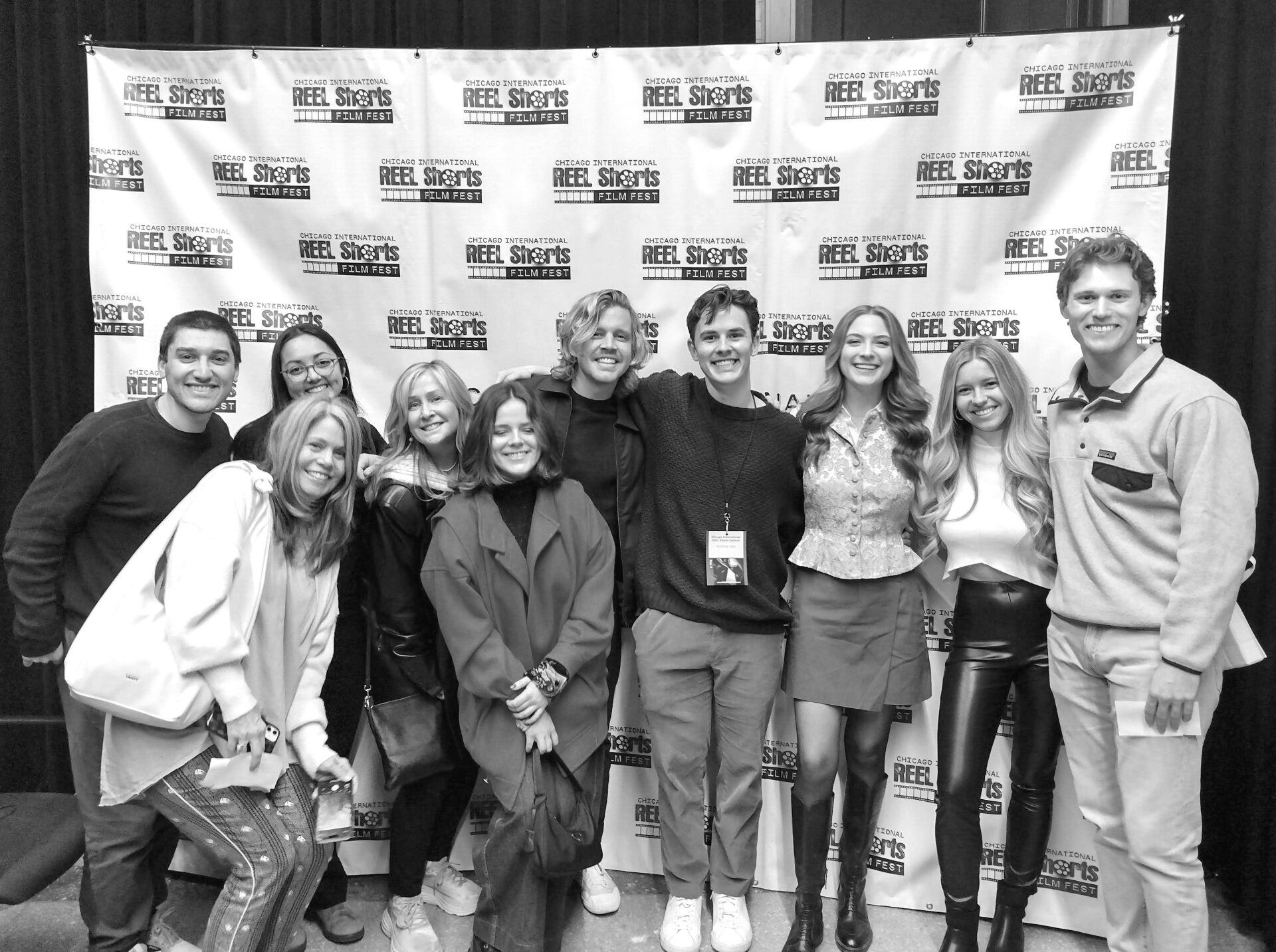 Group of people posing for a photo in front of a sports-related backdrop.
